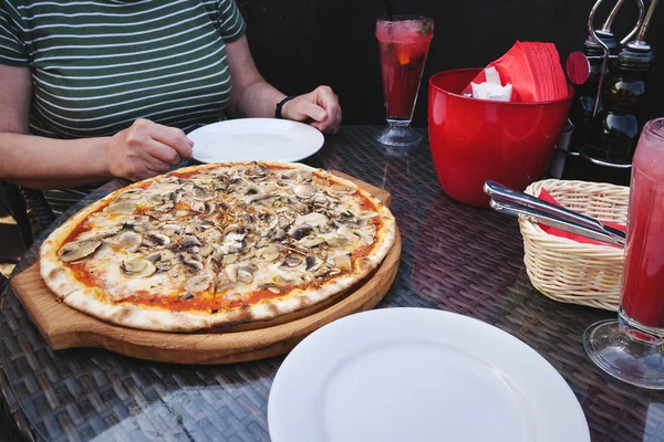 Mushroom pizza in front of woman in restaurant
