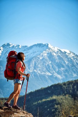 Yaz aylarında kırmızı bir sırt çantası ile yüksek dağlarda yürüyüş.