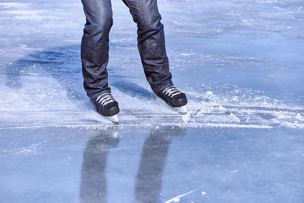 The guy rides on skates on ice in the winter.