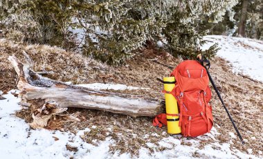 Kırmızı bir sırt çantası içinde bir kış yürüyüş dağlar ve ormanlar fonunda.