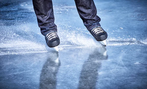 The guy rides on skates on ice in the winter.