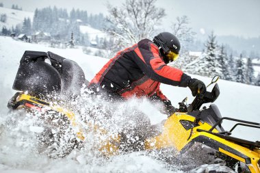 Bir adam bir Atv kışın karda kaskına biniyor.