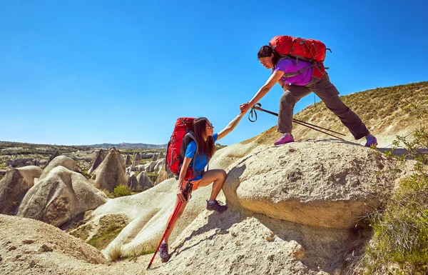 A helping hand for a girl high mountains in a hike.