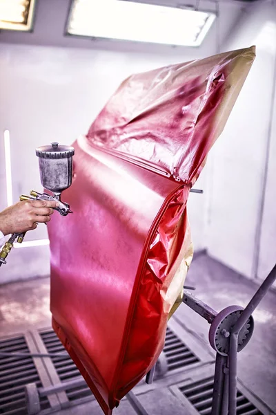 Painting the car door in red color in the painting chamber.