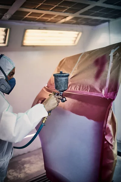 Painting the car door in red color in the painting chamber.