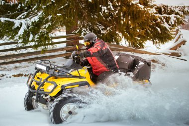 Bir adam bir Atv kışın karda kaskına biniyor.