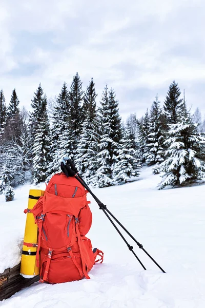 Uma mochila vermelha na neve em uma campanha de inverno contra as costas — Fotografia de Stock