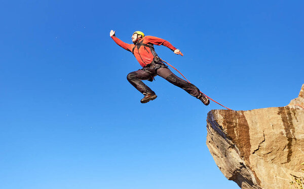 Перейти веревку с высокой скалы в горах
.
