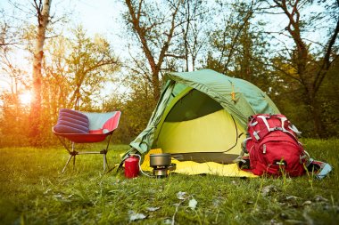 Camping in the woods with a backpack and a tent on the banks of  clipart