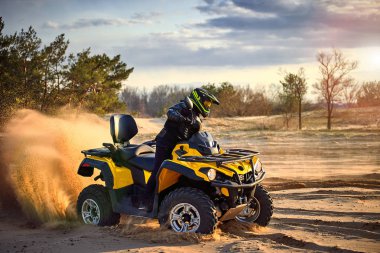 Racing powerful quad bike on the difficult sand in the summer. clipart