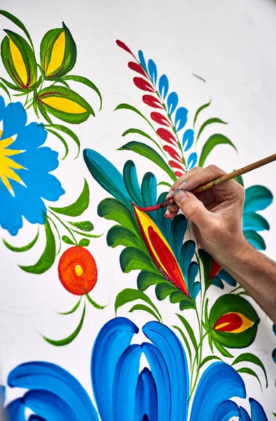 De kunstenaar schildert met olieverf op een witte muur. — Stockfoto