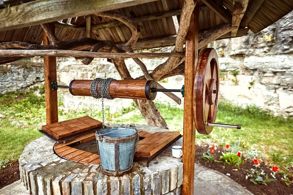 Water well with a wooden roof and a bucket. — Stock Photo, Image