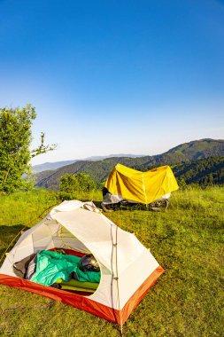 Dağlarda sarı çadırı olan bir motosikletle kamp yapmak..