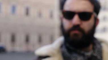 Odaklanamayan sakallı adam kameraya parmağını sokmuyor.