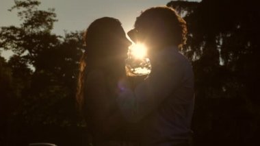 Yaz aşkı: gün batımında parkta öpüşen aşıkların silueti - yavaş çekim