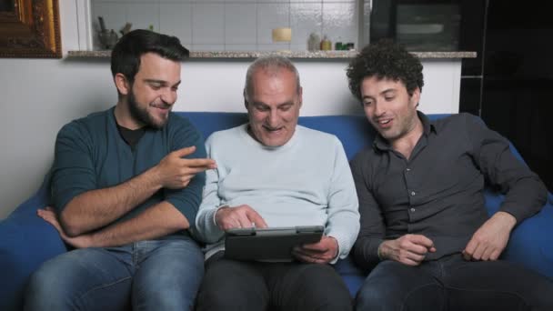 Πατέρας Τους Ενήλικες Γιους Του Κοιτάζοντας Ψηφιακή Ταμπλέτα Στον Καναπέ — Αρχείο Βίντεο