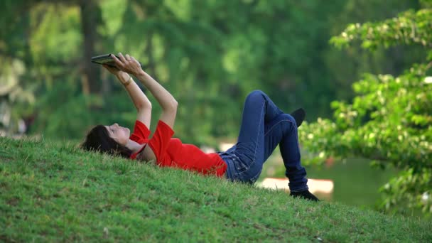 Mooi Zorgeloos Vrouw Liggend Het Gras Maakt Gebruik Van Tablet — Stockvideo