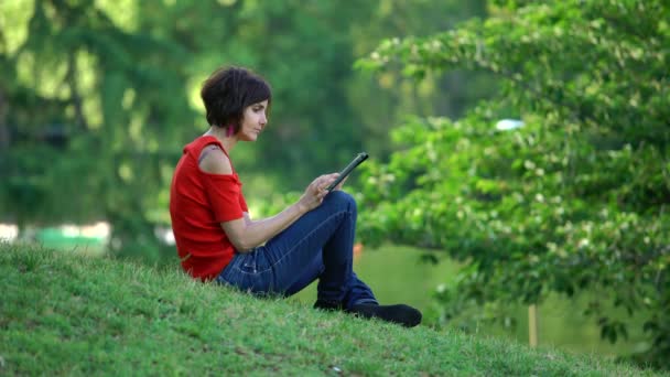 Mujer Hermosa Relajada Sentada Césped Utiliza Tableta — Vídeos de Stock