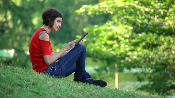 Ung Kvinna Sitter Grön Gräs Träd Parken Använder Tablet — Stockvideo