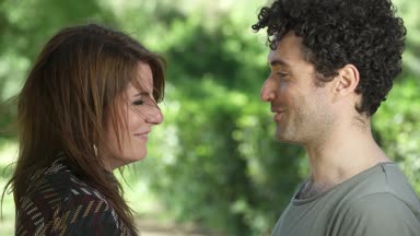 Mutlu çiftin parkta gülüp kucaklaşırken portresi.