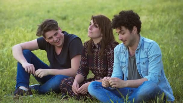 Троє Молодих Друзів Розслабляються Сидячи Галявині Спілкуючись Сміючись Розслабляючись — стокове відео