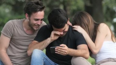 Kahkaha, kaygısız neşe - parktaki arkadaşlar akıllı telefona bakıp gülüyorlar