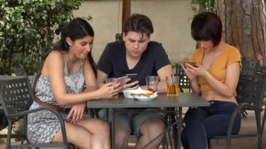 Genç konuşuyor arkadaş ve Smartphone oturan Cafe içinde kullanma