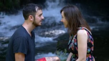 adam ve kadın ağaç gövde, orman ve şelale üzerinde flört