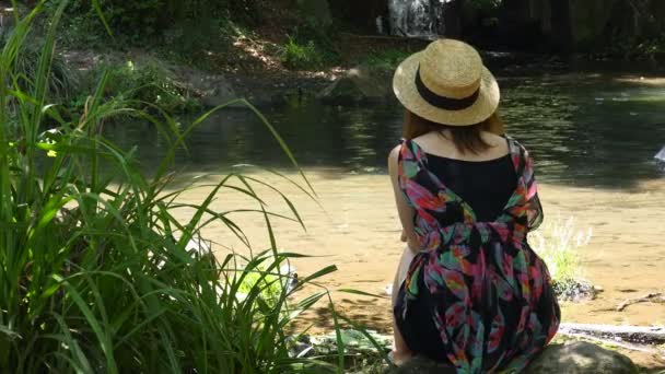 女人坐在河岸上 接触大自然 — 图库视频影像