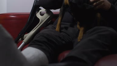 Olgun adam kanepede kırık bir bacak ile köpek okşadı