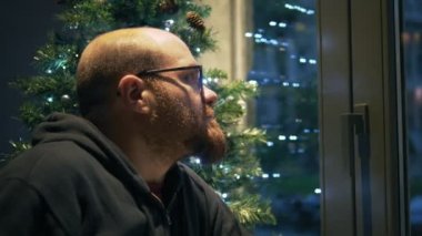 Noel'de yalnız genç adam pencereden depresif