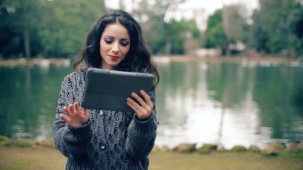 在公园里使用平板电脑的微笑迷人的年轻妇女的肖像 — 图库视频影像