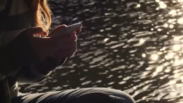 Mulher Relaxada Digitando Seu Smartphone Perto Rio Pôr Sol — Vídeo de Stock