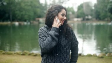 gülümseyen çekici genç kadın parkta telefonla konuşuyor
