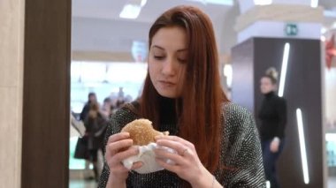 bir fast food restoran büyük bir hamburger yeme aç genç kadın