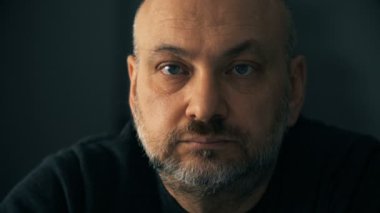 Karanlıkta kamera bakan dalgın olgun adam. Düşünceler, sorunları