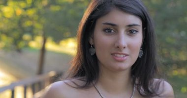 Genç güzel kadın gülümseyerek için kamera In Park ın yaz gün 