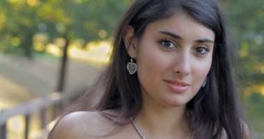 Kafasını çevirerek ve kamera-açık gülümseyen Latin güzel genç kadın