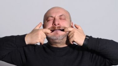 Komik komik kel adam o ağzını elleriyle yayılıyor. Komedi, şaka, eğlenceli