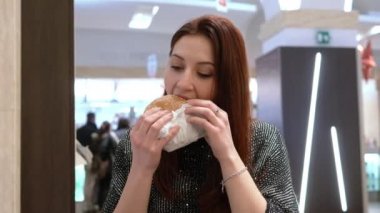 Aç genç kadın byting bir fast food büyük bir hamburger güzel