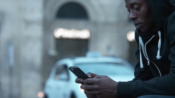 Joven Encapuchado Negro Africano Hombre Escribiendo Smartphone Aire Libre — Vídeo de stock