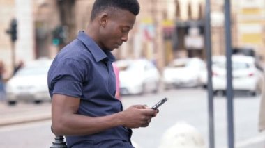 Genç Amerikan Afrika adam akıllı telefon sokakta yazarak üzerinde duruldu
