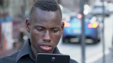 Mutlu gülümseyen Afrika adam sokakta onun dijital tablet arıyorsunuz