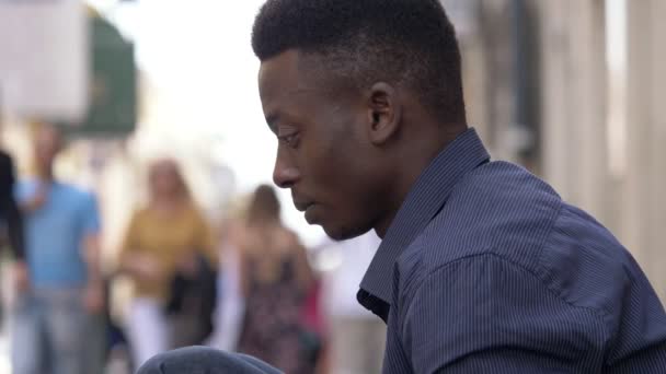 沉思的年轻黑人美国人认为坐在街上 — 图库视频影像