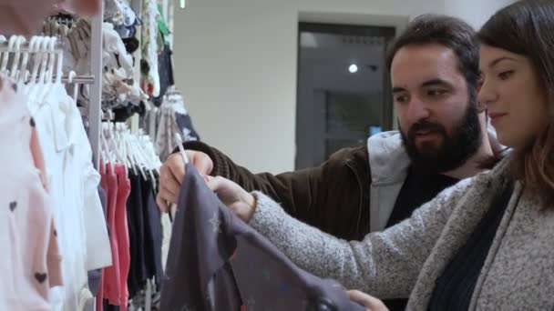 Young Couple Expecting Baby Baby Shop Choosing Dress — Stock Video