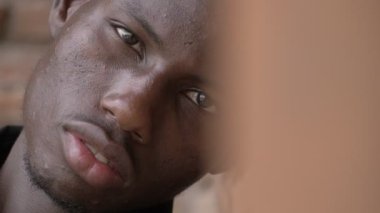 Kameraya bakarak duvara yaslanmış depresif üzgün siyah Amerikalı genç bir adam