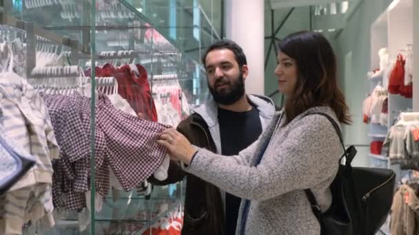 Mujer Embarazada Con Marido Eligiendo Ropa Para Niños Una Tienda — Vídeo de stock