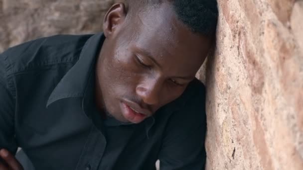 Глубокая Депрессия Молодой Чернокожий Мужчина Наклоняется Стене Смотрит Камеру — стоковое видео