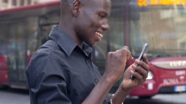 gülümseyen rahat siyah Amerikalı adam onun smartphone şehrin yazarak