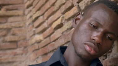 duvara yaslanmış yalnız hüzünlü düşünceli genç Afrika göçmen